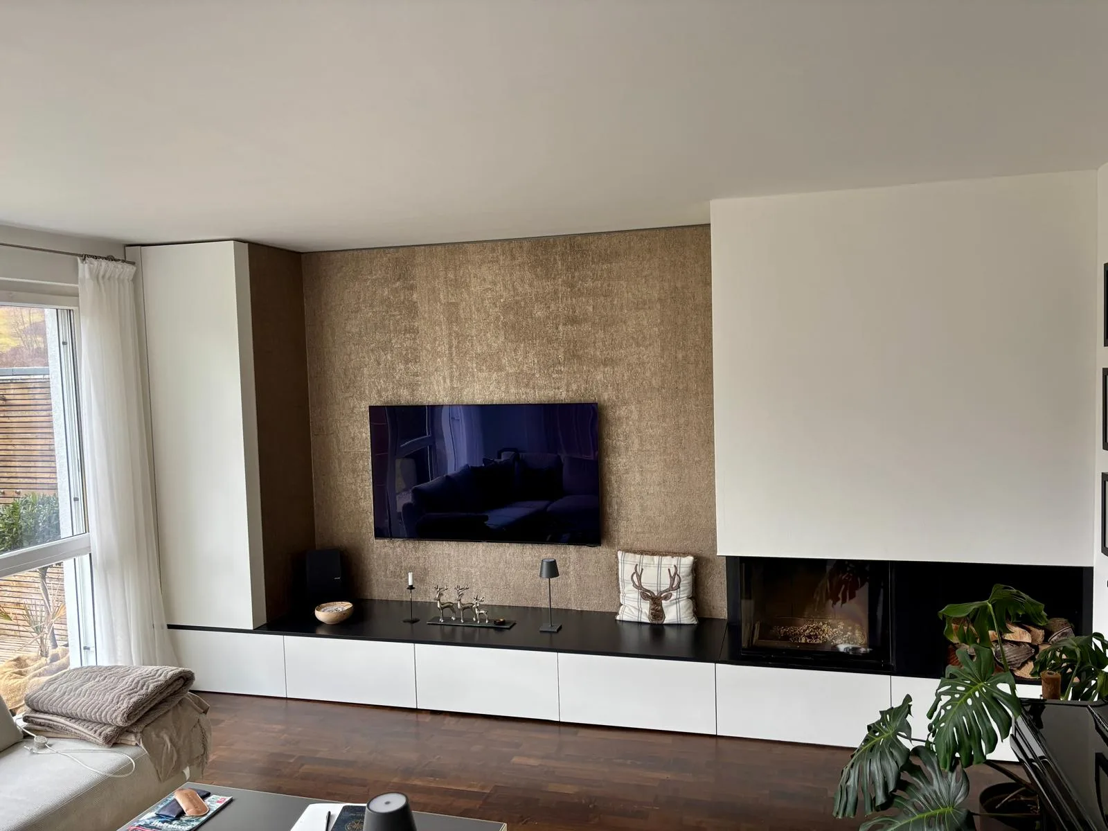 Umgesetzte Wohnwand mit TV, weißem Sideboard, schwarzer Abdeckung und Kamin